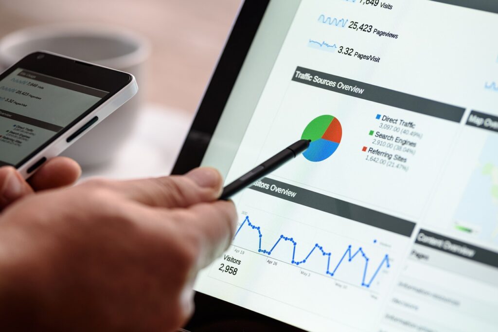 Person analyzing digital marketing data on a tablet and pointing to a pie chart representing traffic sources.