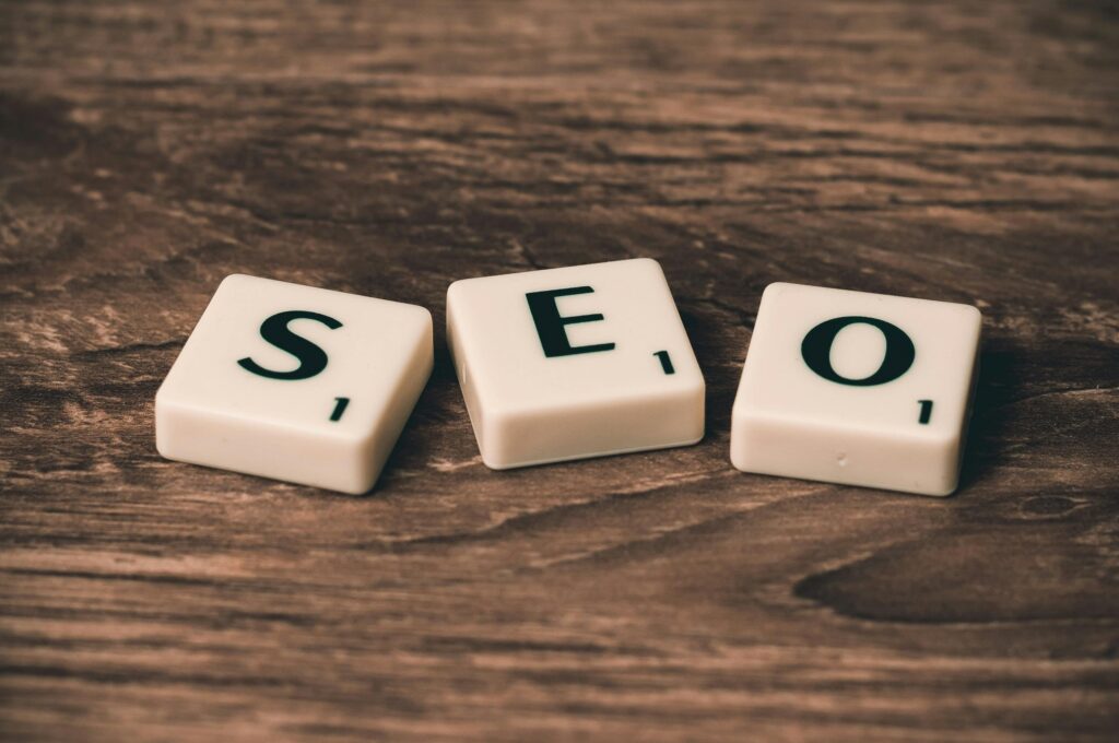 Three White-and-black Scrabble Tiles on Brown Wooden Surface that spell out SEO.
